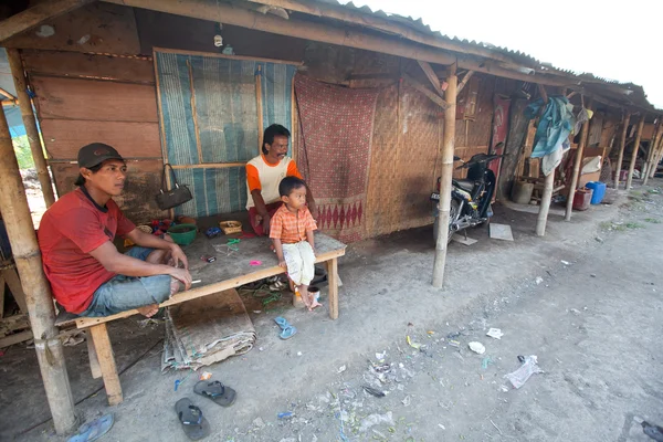 BALI, INDONÉSIA 11 DE ABRIL: Crianças não identificadas estão sentadas durante seus pais estão trabalhando em uma escavação na lixeira em 11 de abril de 2012 em Bali. Bali produziu diariamente 10.000 metros cúbicos de resíduos . — Fotografia de Stock